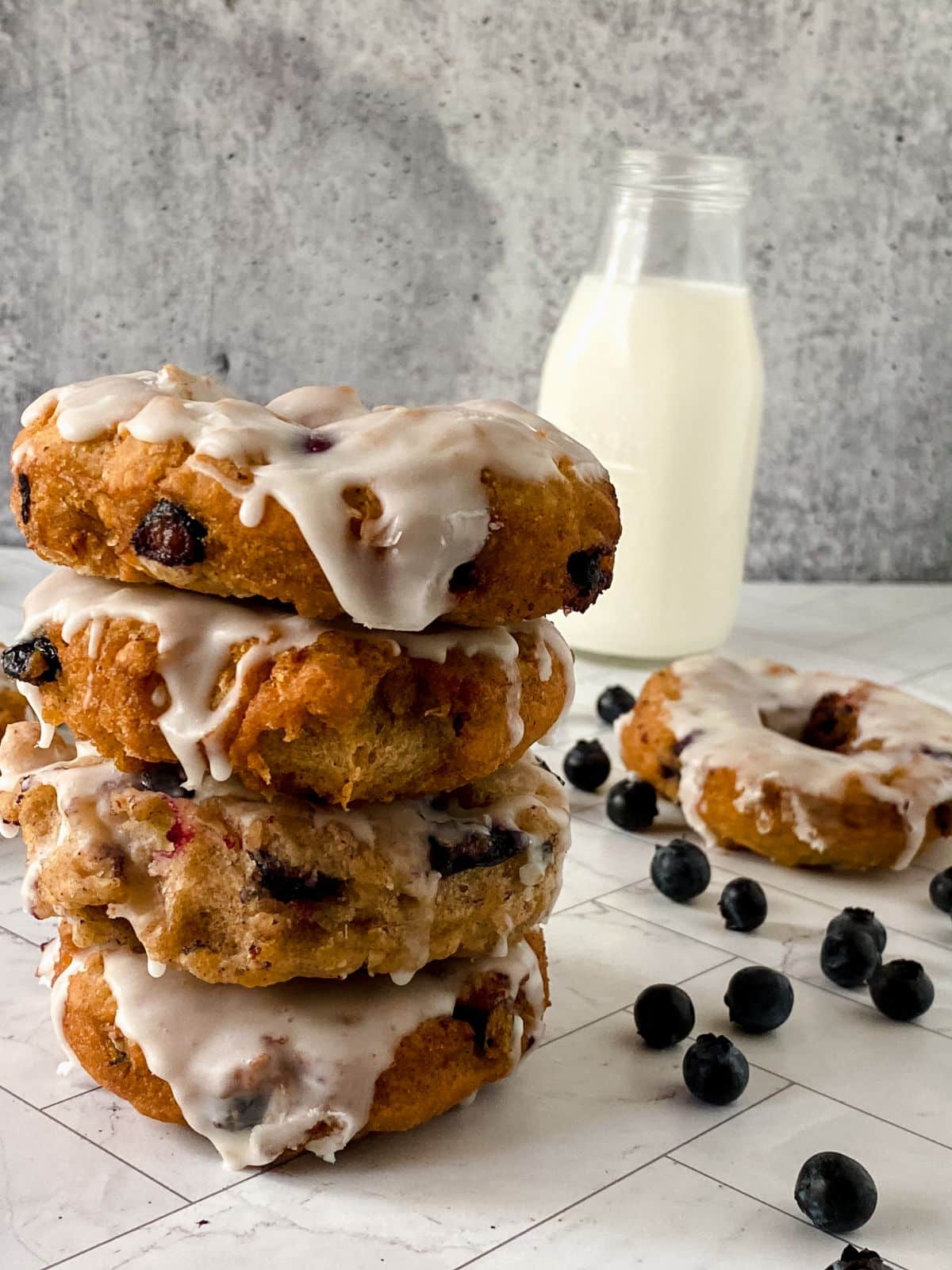 stack of blueberry donuts on marble table with milk in background