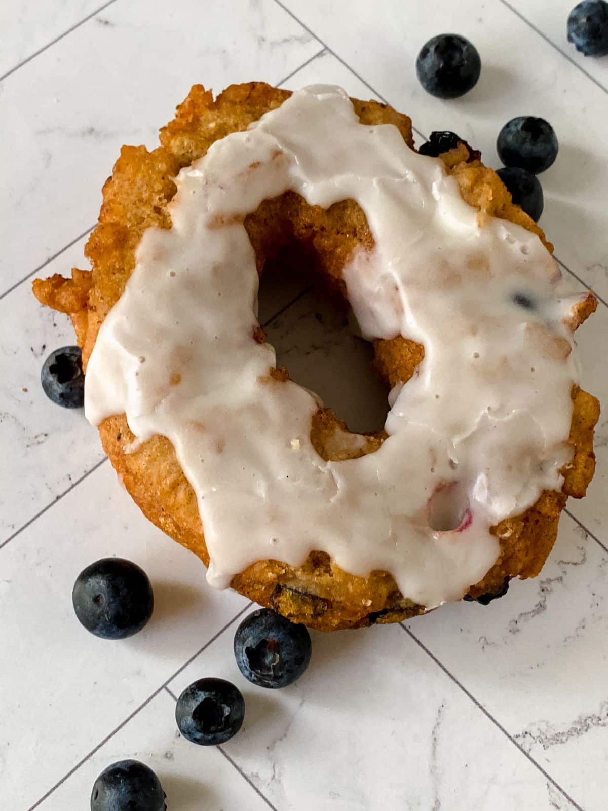 single blueberry cake donut with glaze on table