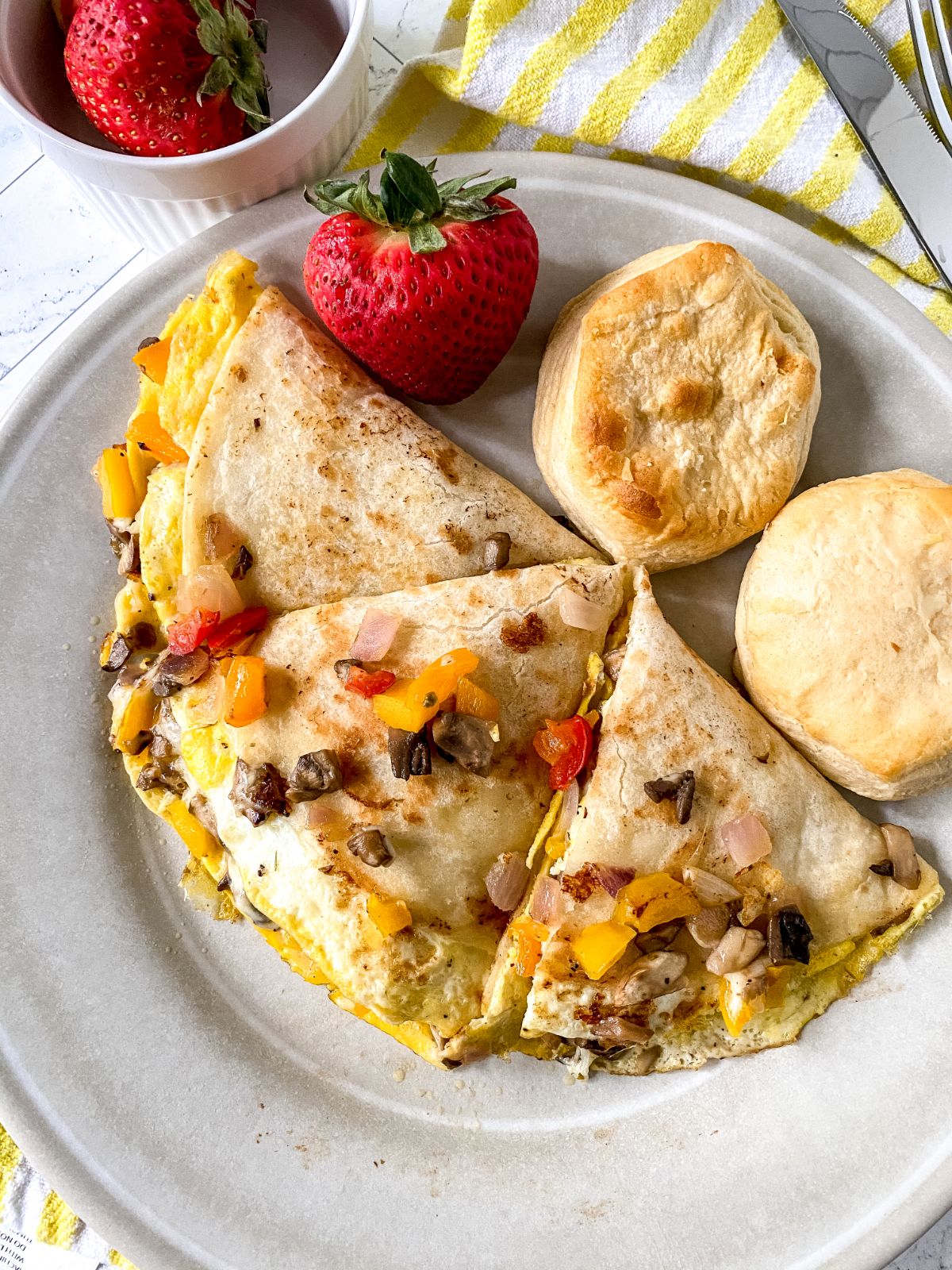 beige plate with breakfast quesadilla and berries