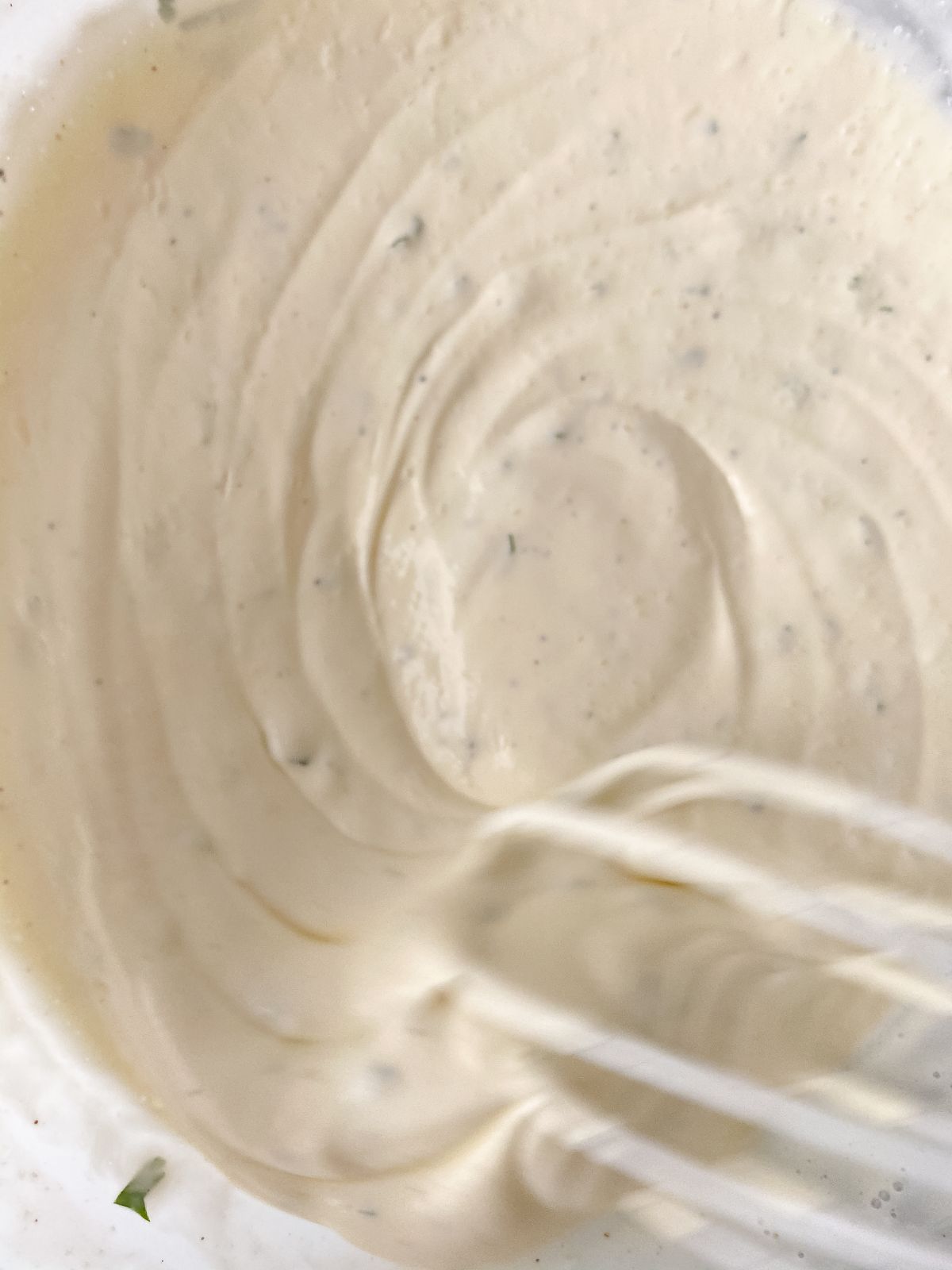 whisk in bowl of creamy sauce