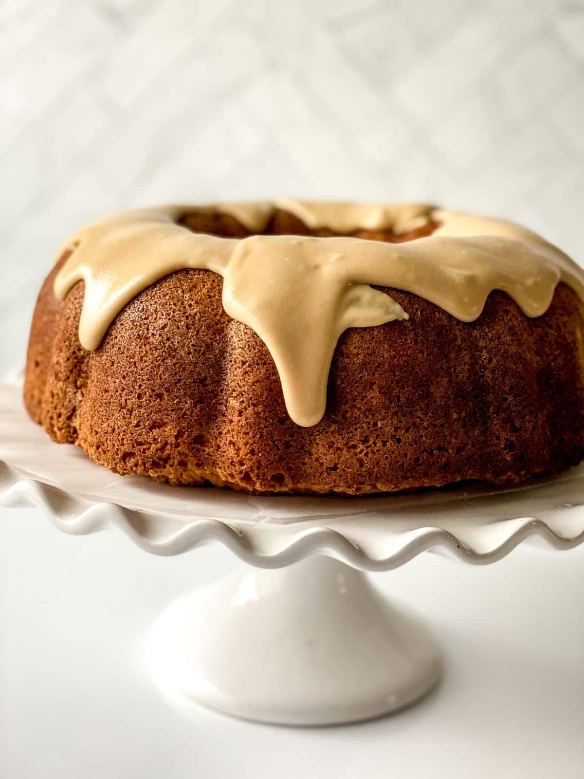 buttermilk pound cake covered with caramel glaze on white cake stand