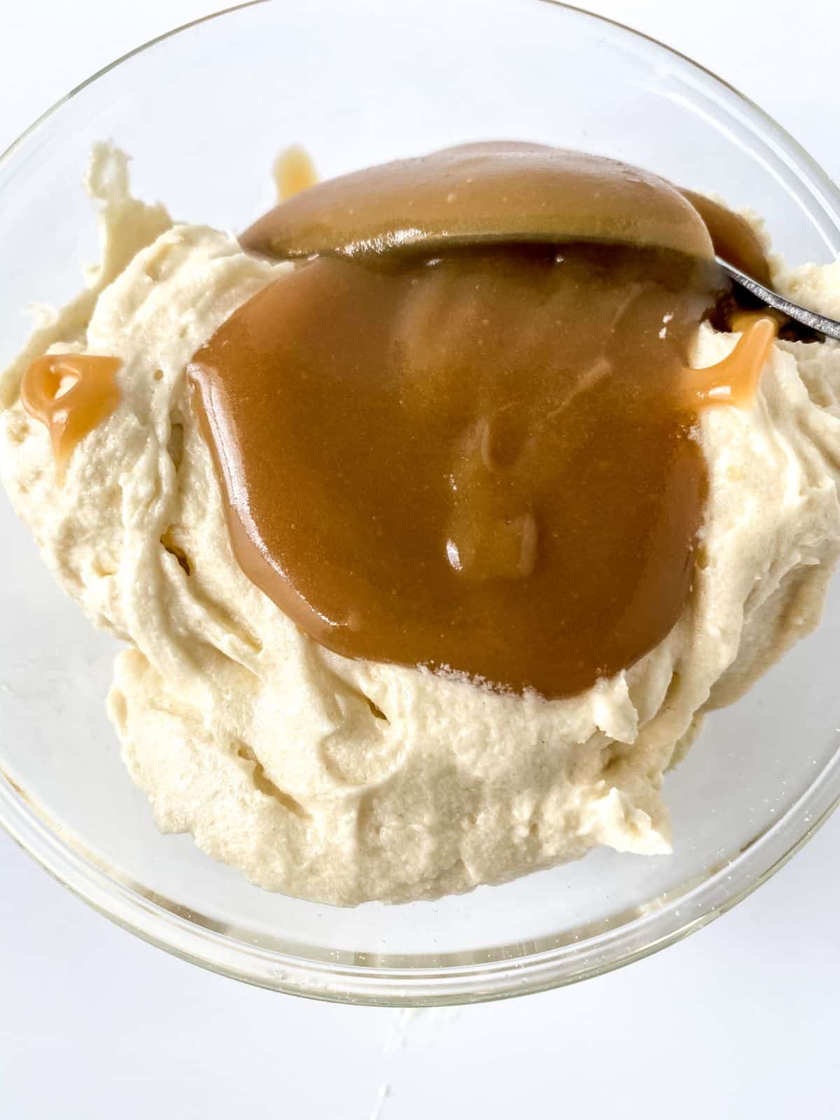 caramel sauce being added to batter in glass bowl