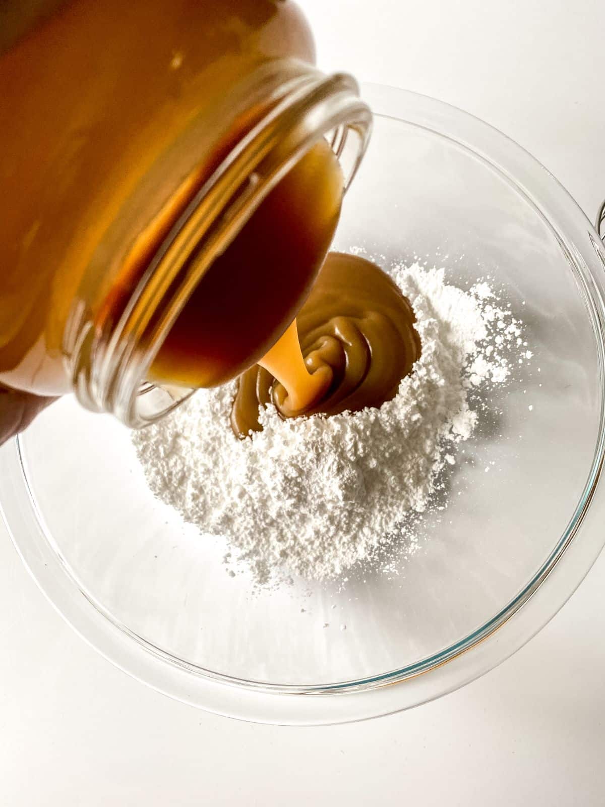 caramel sauce being poured into powdered sugar