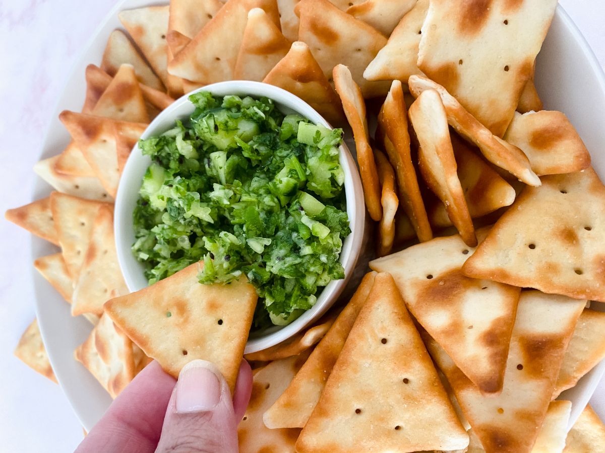 pita chip being dipped into green relish