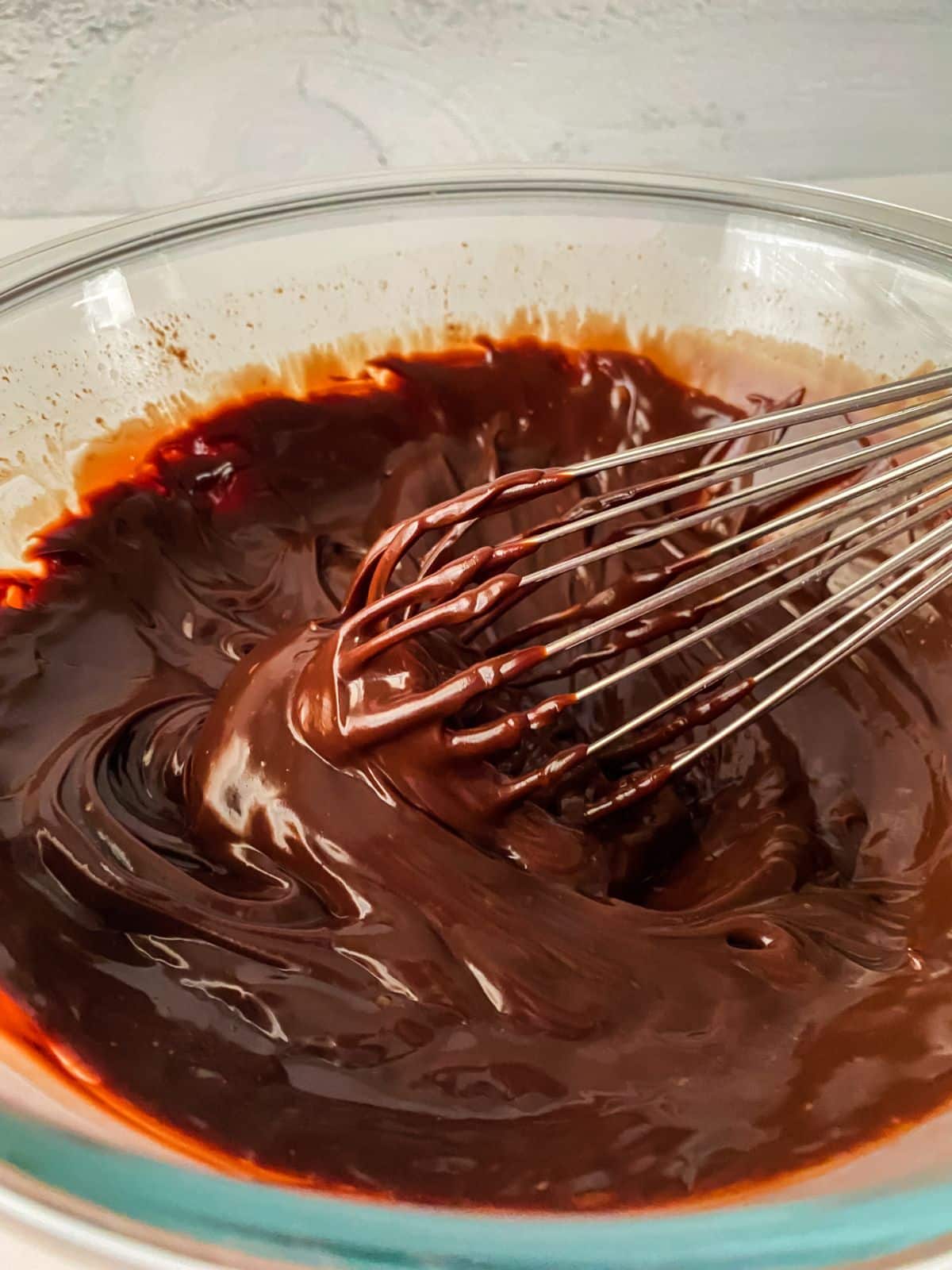 metal whisk in glass bowl of chocolate