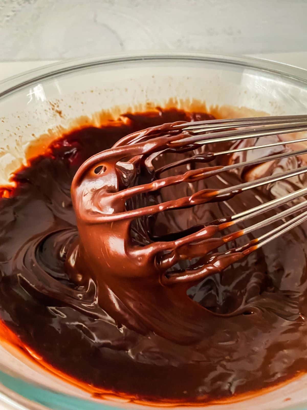whisk held above bowl of chocolate ganache
