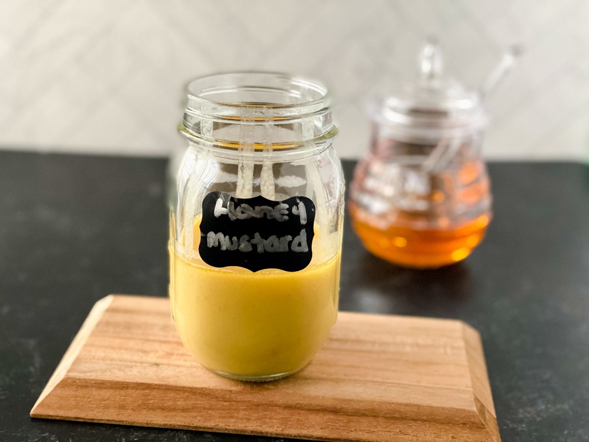 cutting board on black table with honey mustard in jar