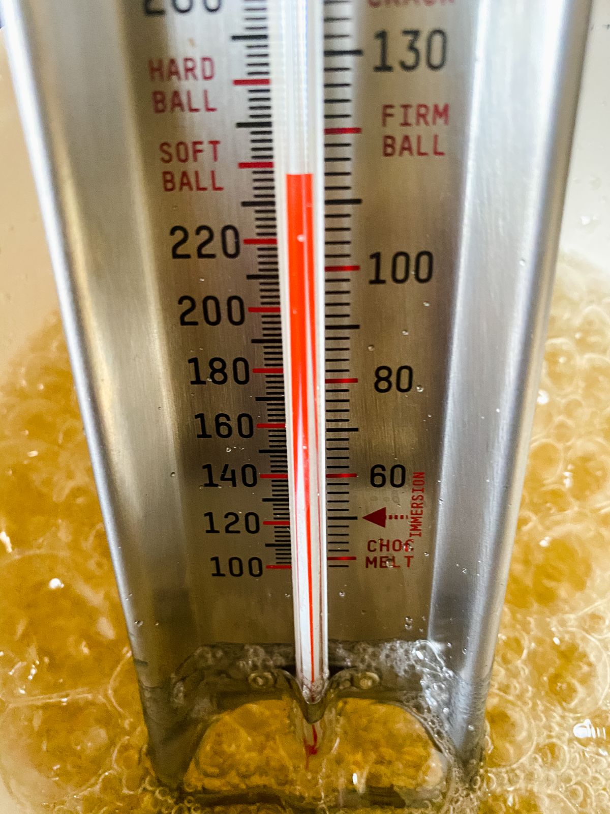 candy thermometer showing temperature in melted sugar