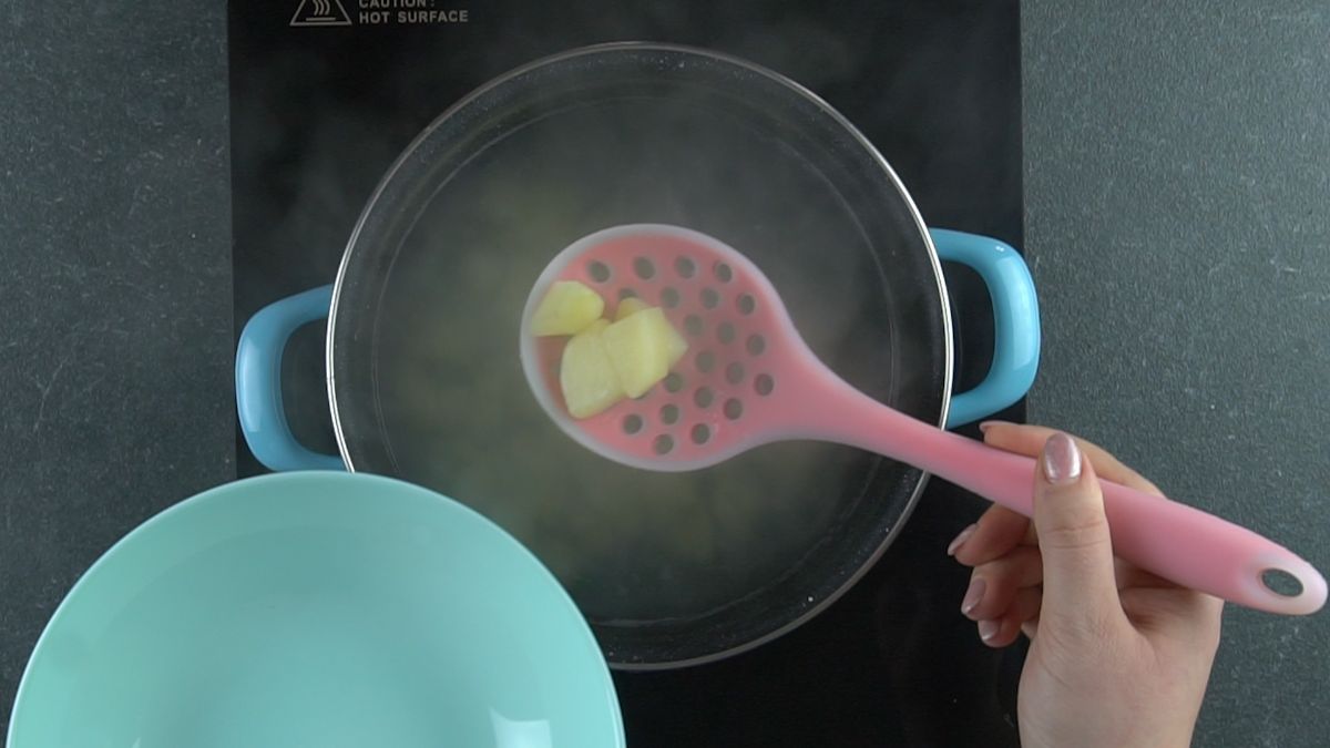 potatoes in pink slotted spoon above boiling water