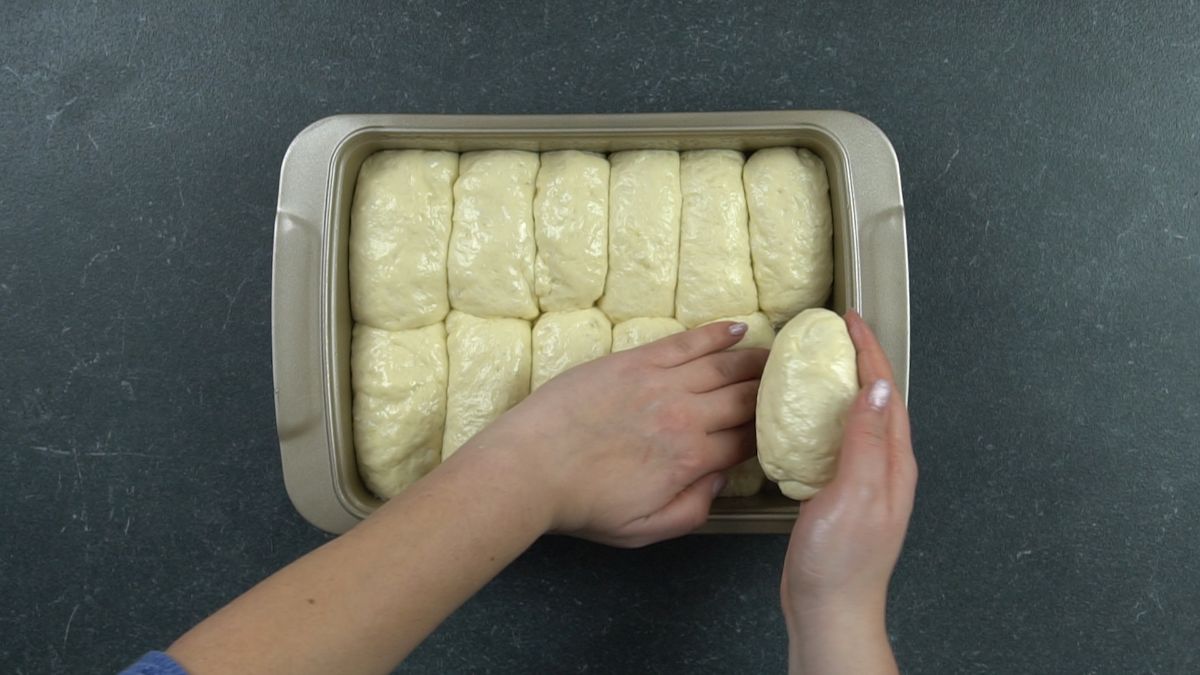 hand putting bread dough into baking dish