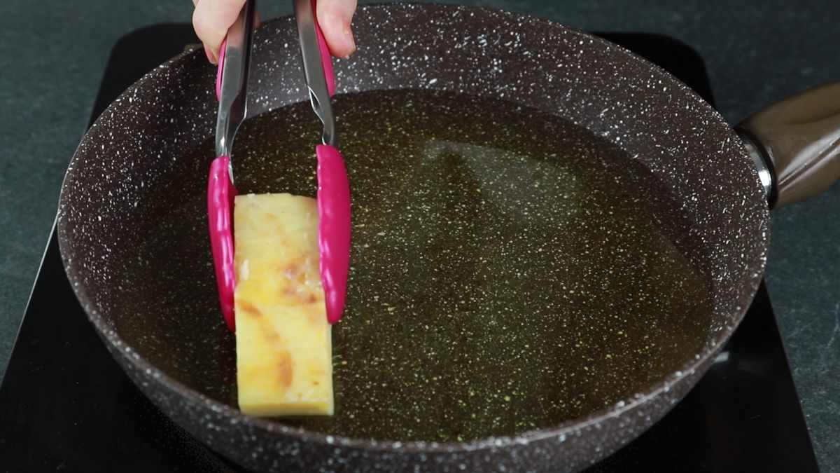 tongs putting potato terrine slice into hot oil