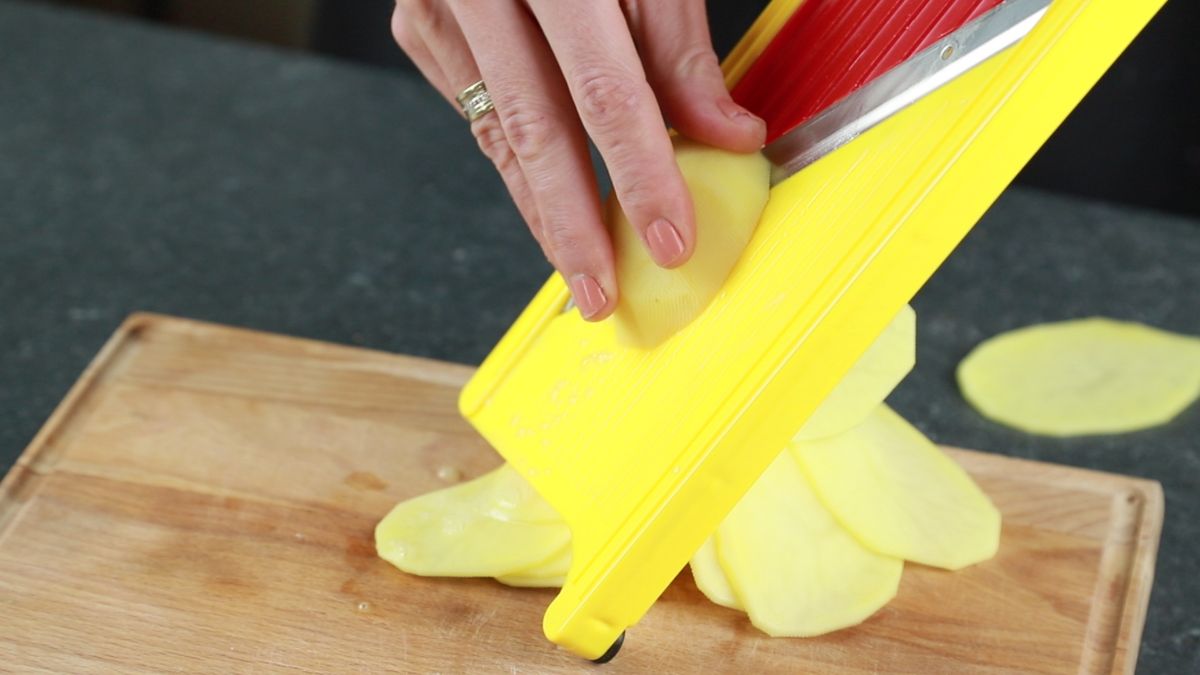red and yellow mandolin slicing potatoes