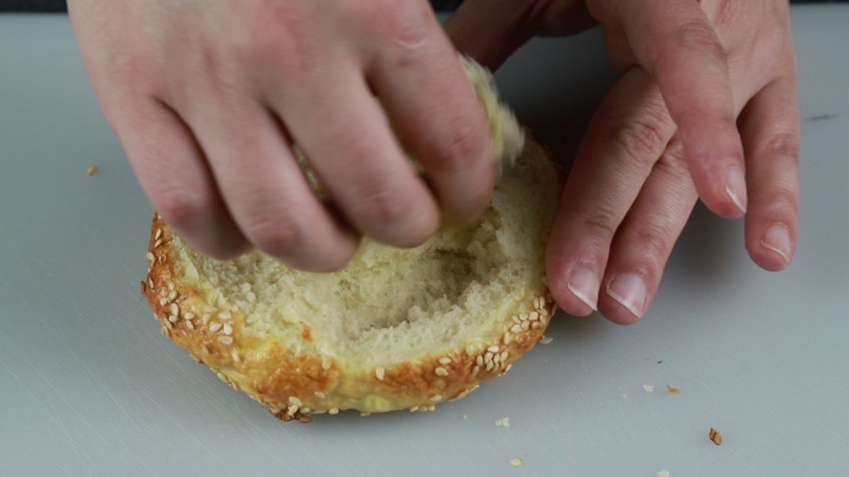 hand pulling middle of bagel out