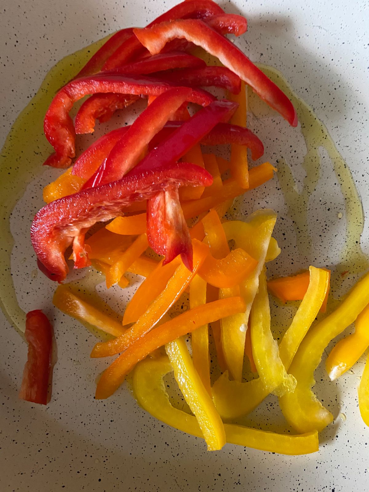 red yellow and orange bell pepper slices in white skillet