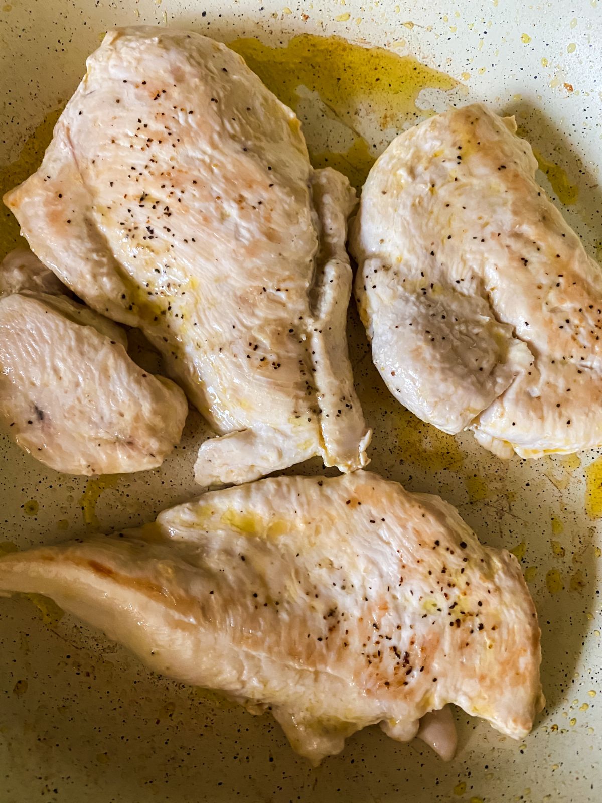 chicken being cooked in white skillet