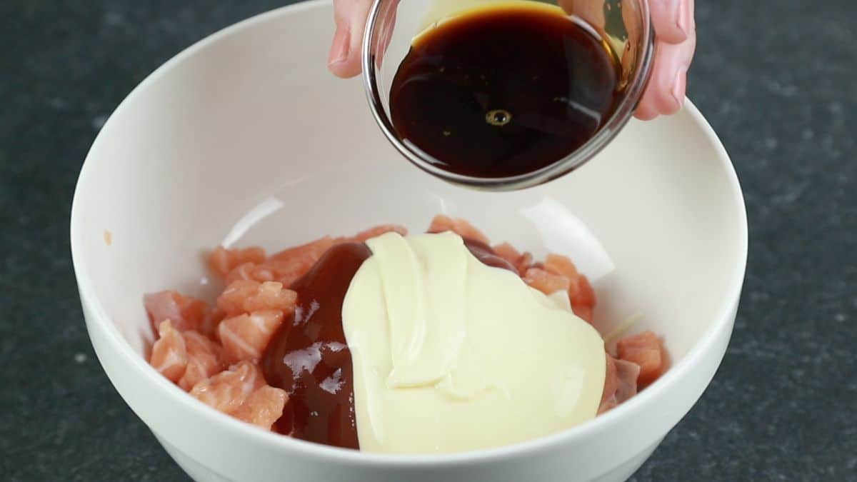 soy sauce being added to white bowl of mayonnaise and salmon