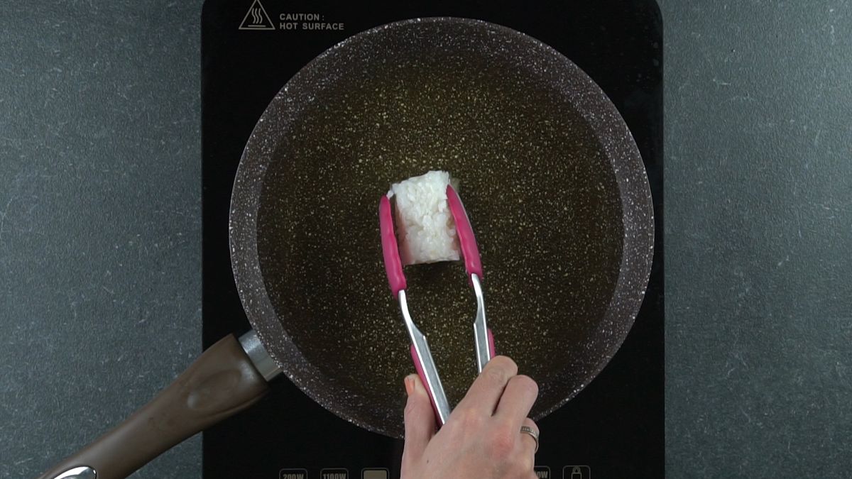 placing rice into hot oil in skillet