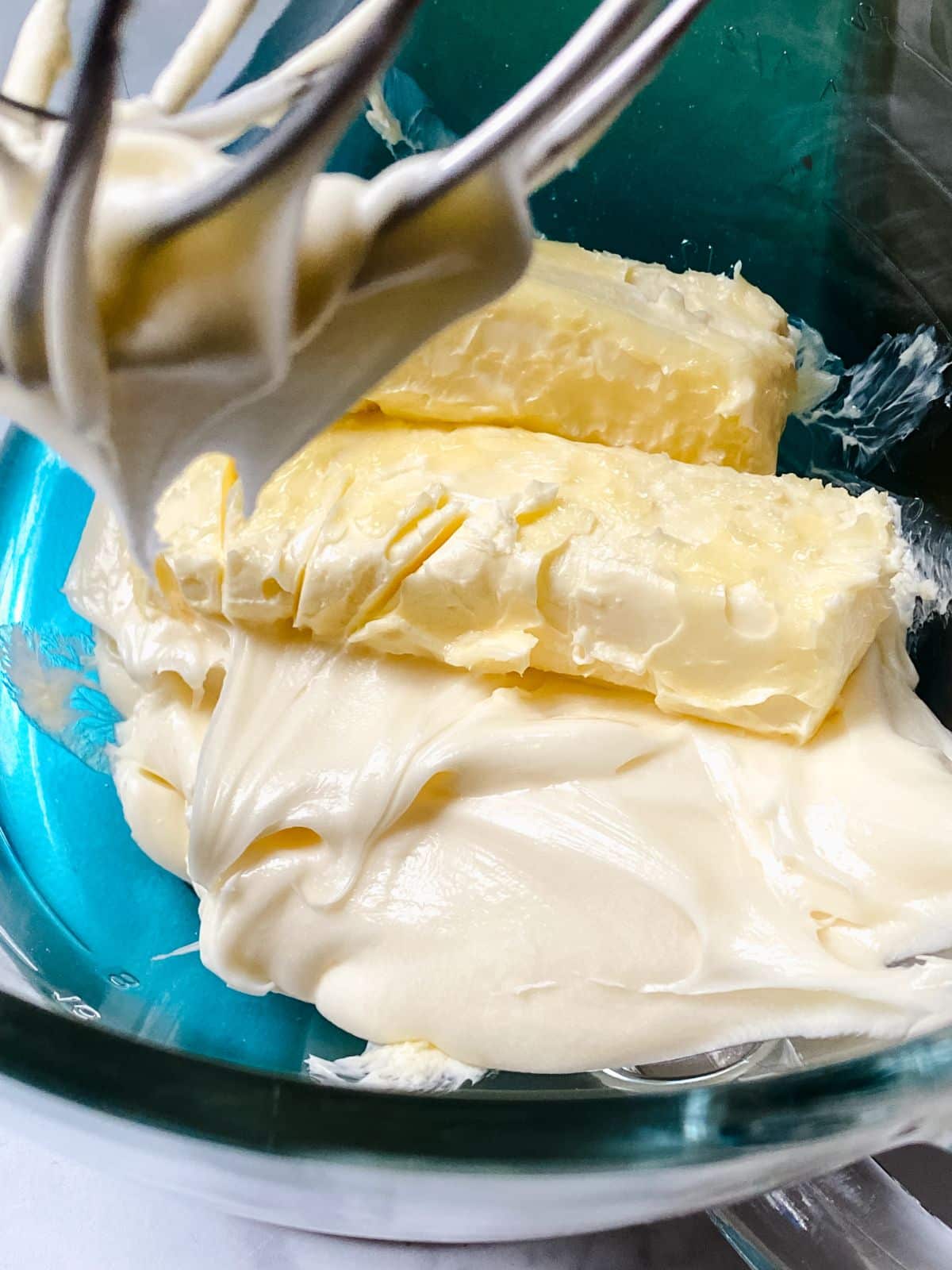 frosting and butter in bowl with whisk