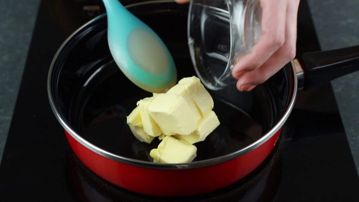 butter being added to red skillet on hot plate
