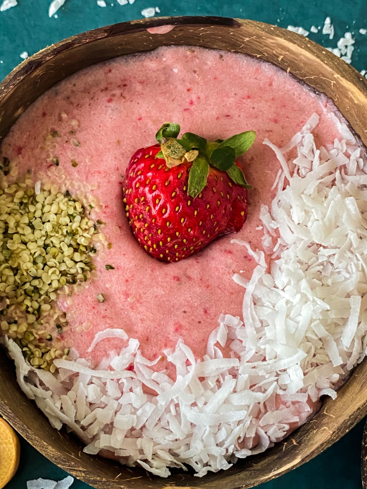 smoothie bowl topped with shredded coconut chia seeds and a whole strawberry
