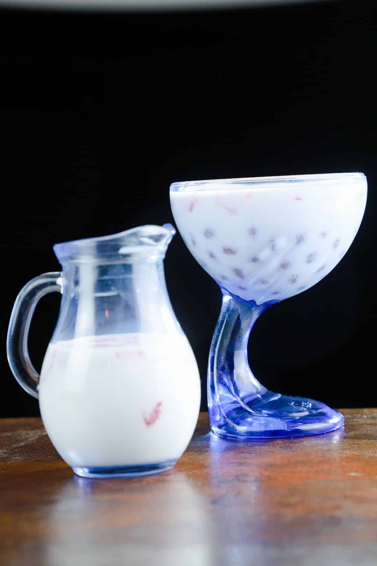 blue glass of strawberry boba milk with black background