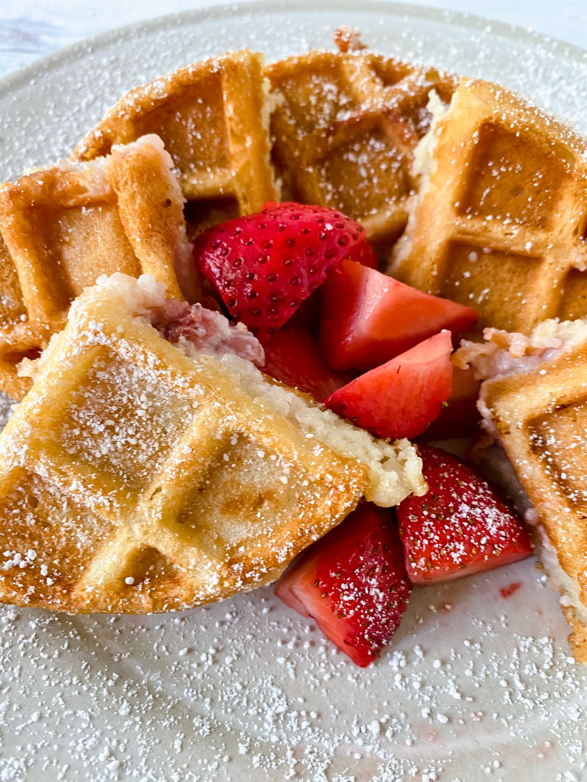 cream plate of waffles with berries and powdered sugar