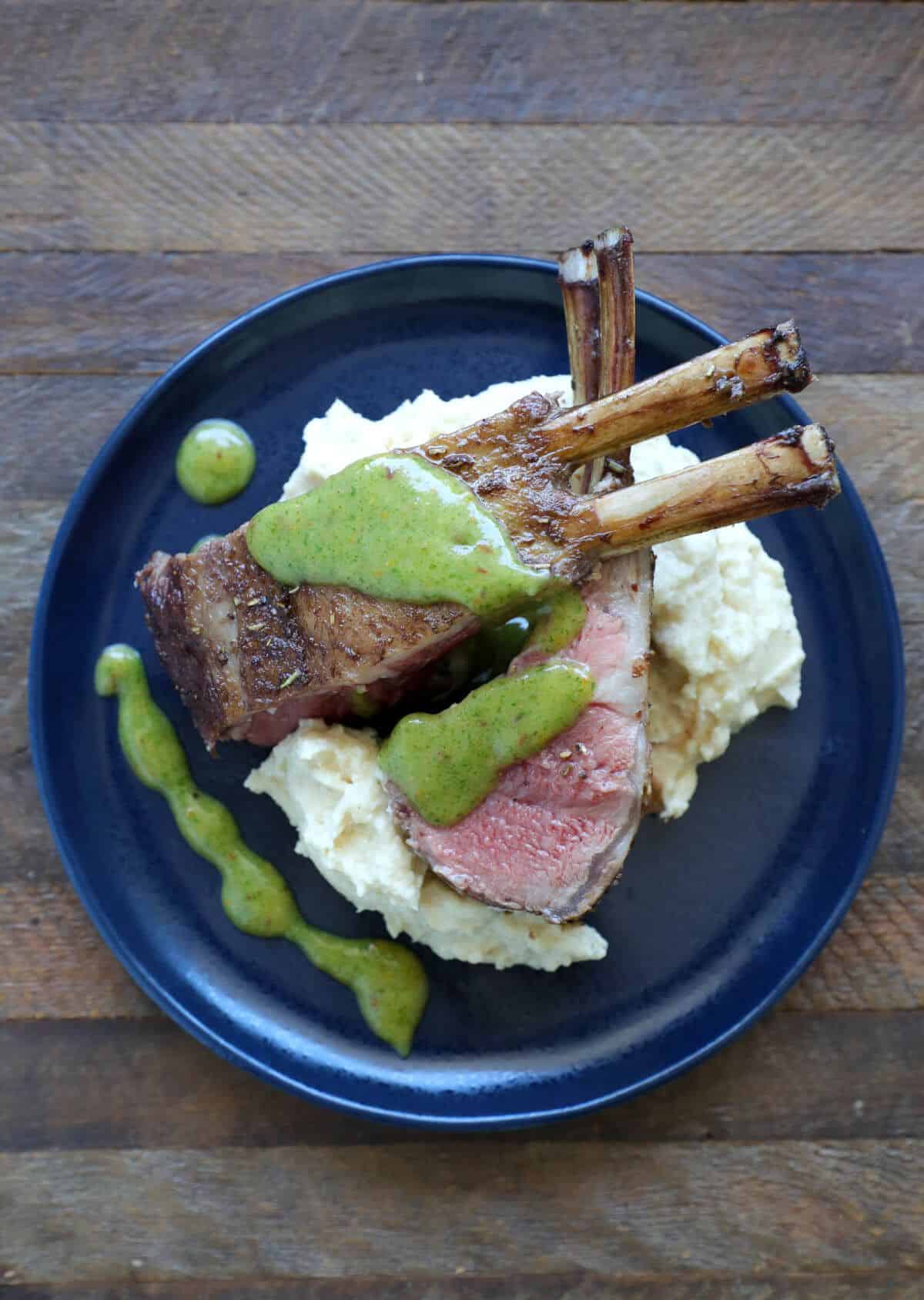 Keto Rack of Lamb with Spicy Mint Marmalade on a black plate on a wooden table.