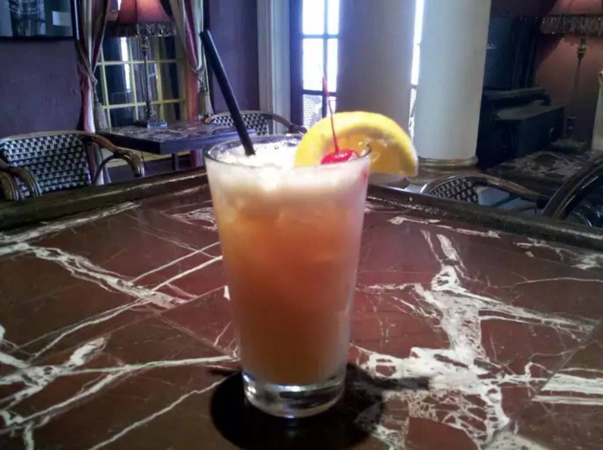 Rum Runner rum coctail with a slice of lemon and a straw in glass cup.