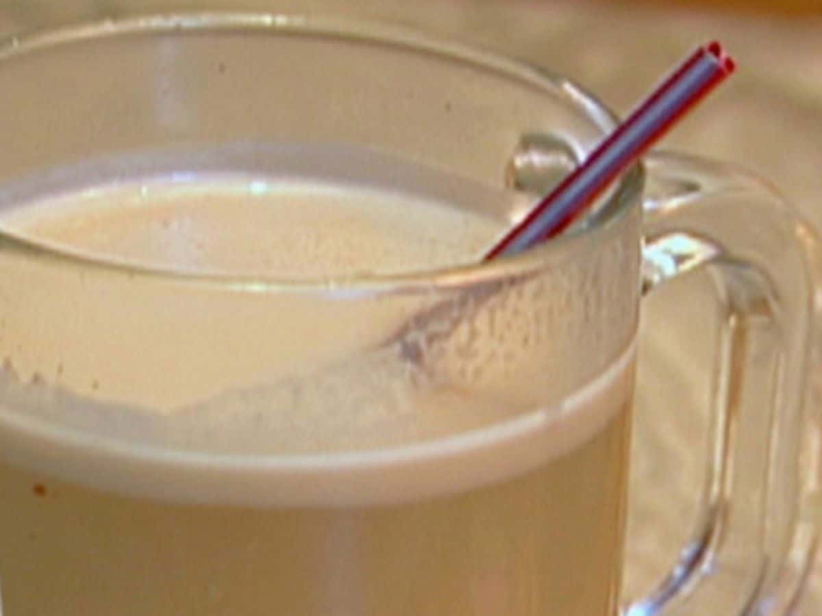 Hot Buttered Rum coctail in a glass cup with a straw.