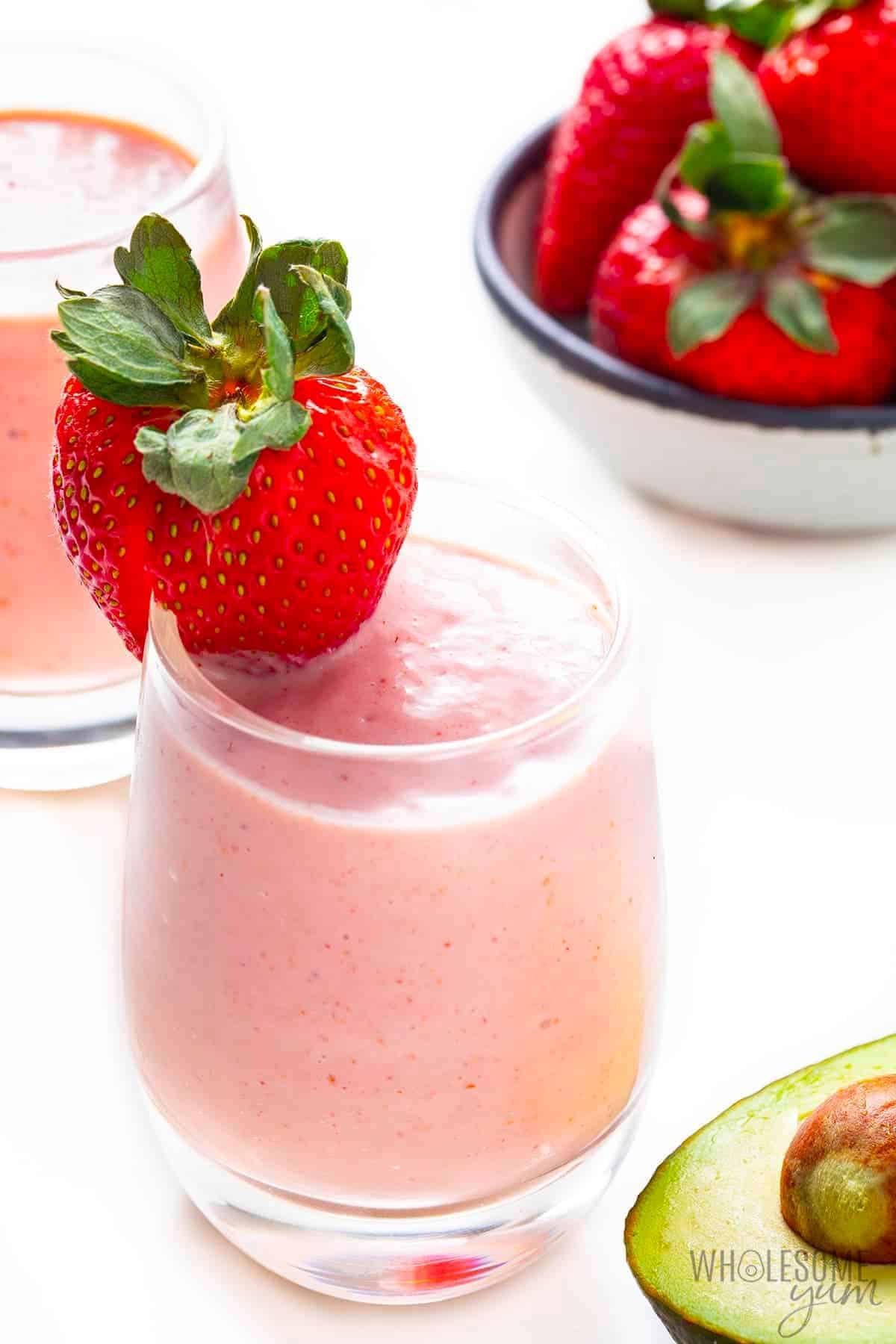 Strawberry Avocado Keto Smoothie in a glass cup with a strawberry on the top.