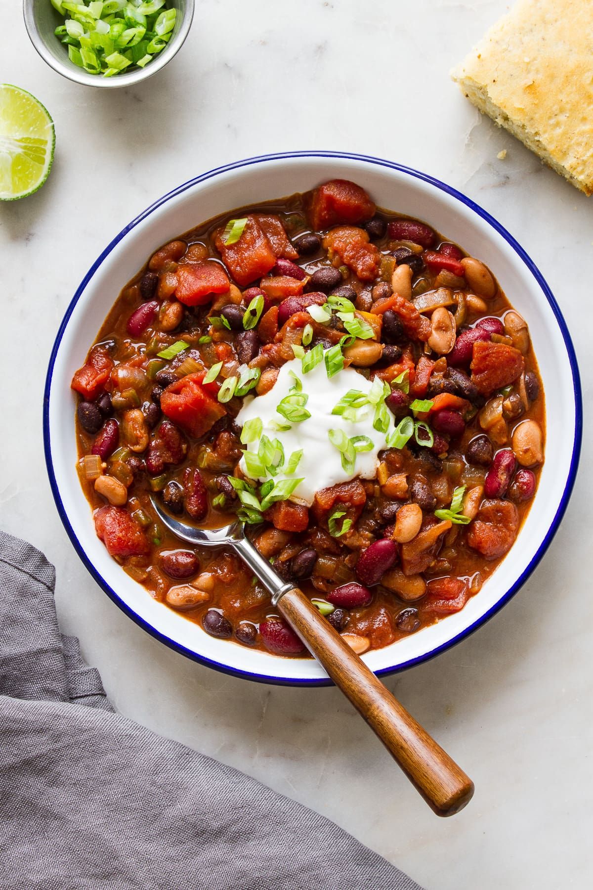 Three Bean Chili in a white bowl with blue edges and a spoon.