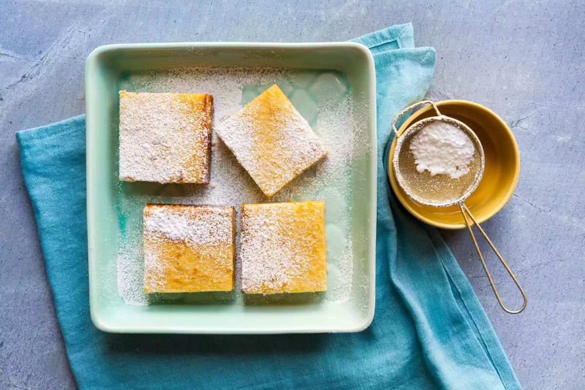 Keto Lemon Bars in a green bowl on a blue piece of cloth.