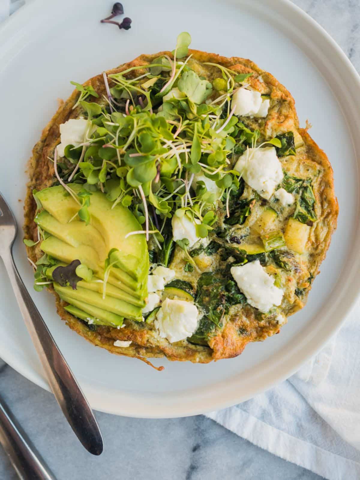 Super Greens Frittata on a white plate with a fork.