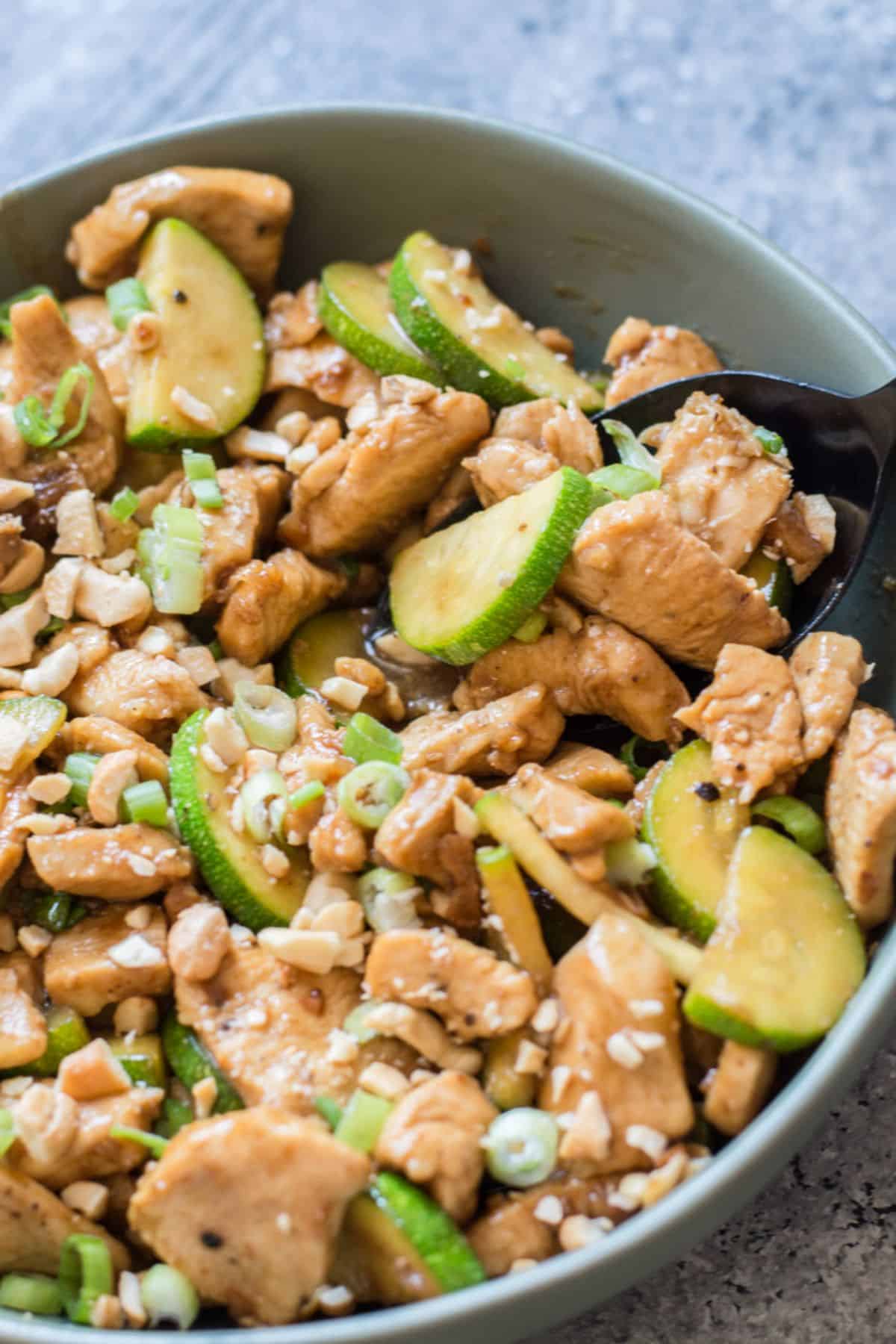 Sesame Chicken Keto Stir-Fry in a gray bowl with a spoon.
