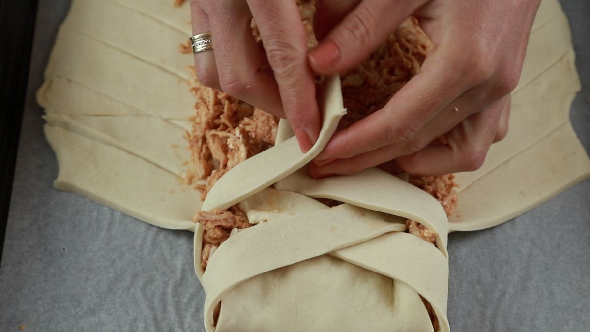 hand folding dough over chicken filling