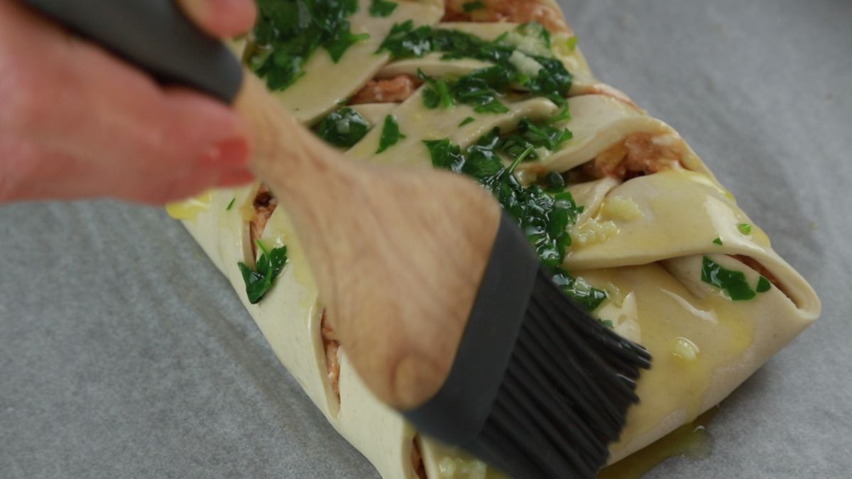 pastry brush putting garlic and parsley butter over pastry