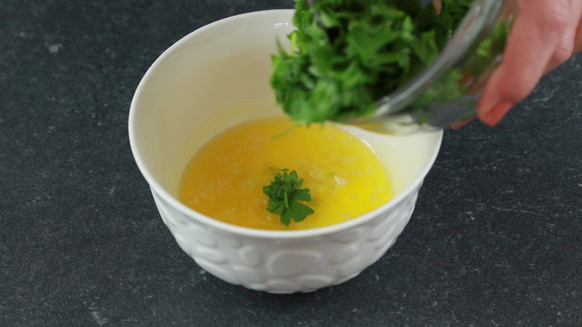 parsley being added to bowl of butter