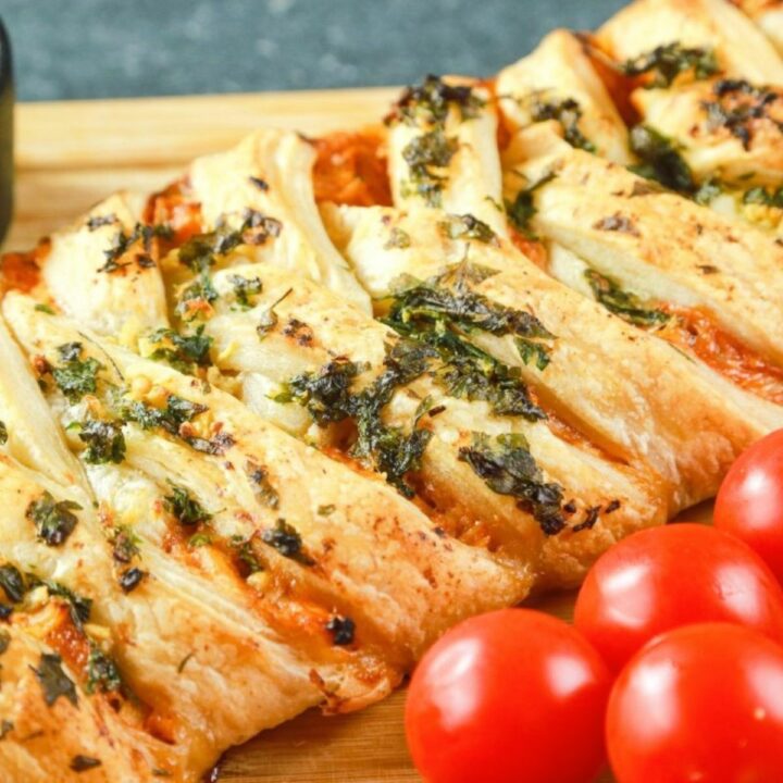 puff pastry chicken braid on cutting board by tomatoes