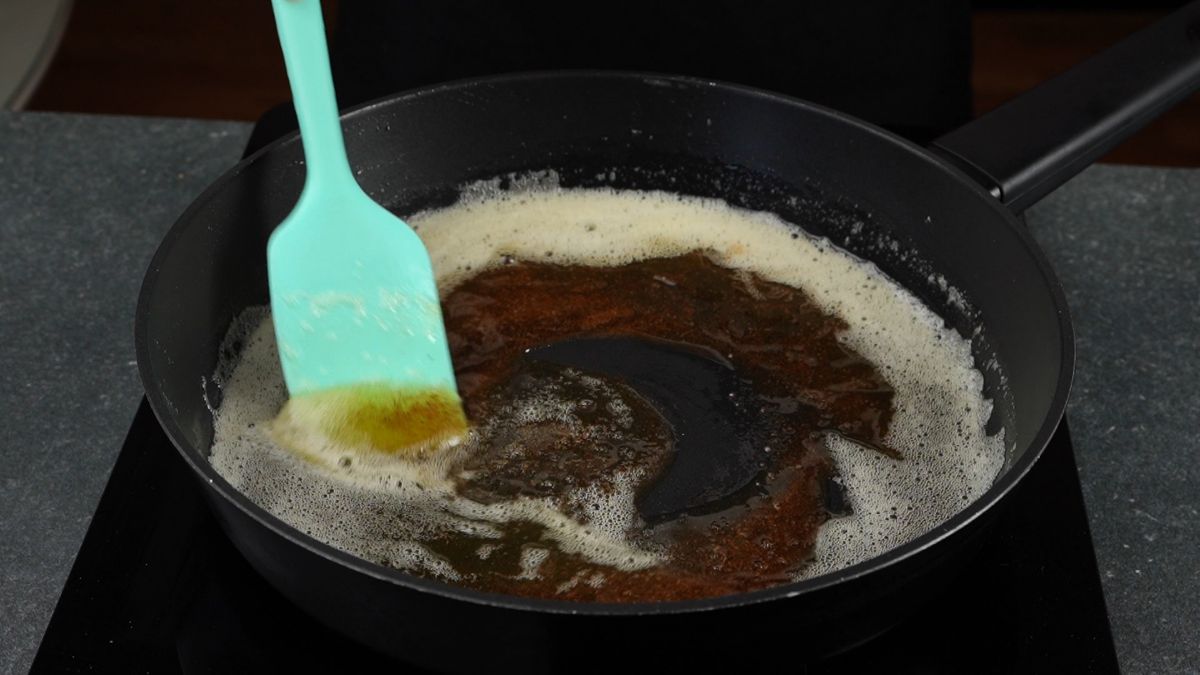 b ue spatula stirring brown butter in cast iron skllet