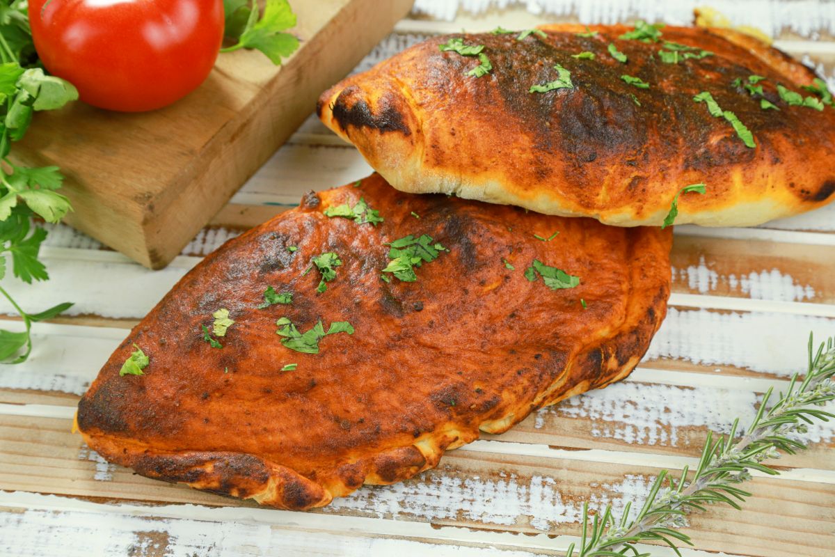 calzones on wood table by cutting board