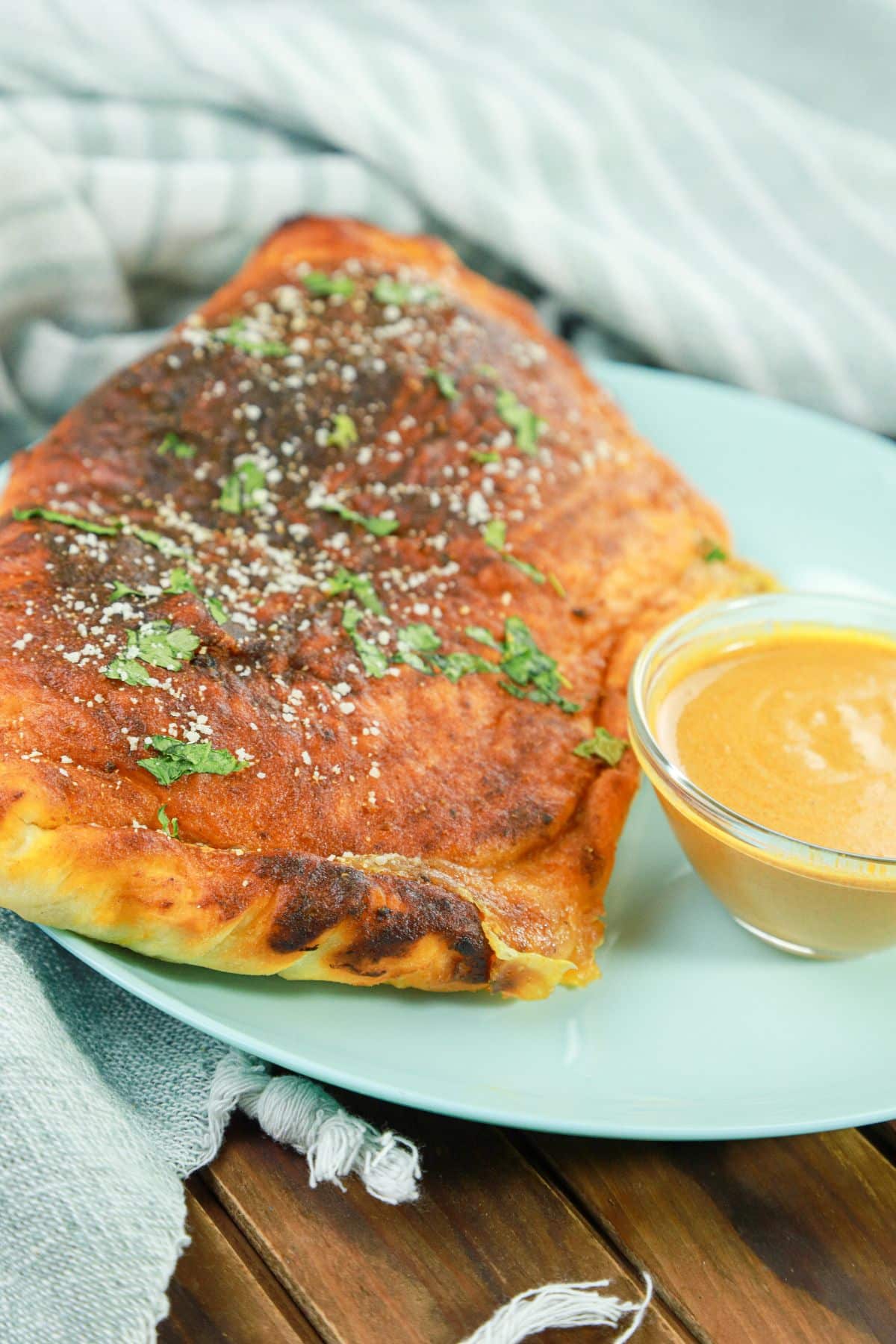 calzone on plate by dipping sauce