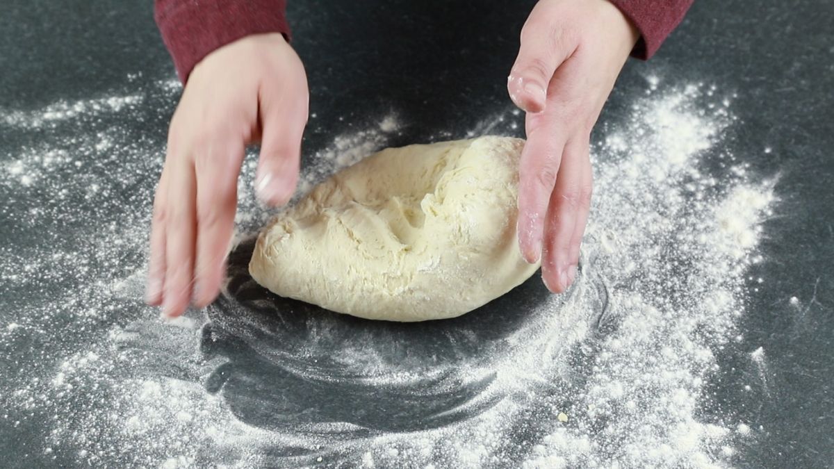 hands kneading dough on counter