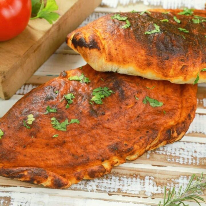 calzones on wood table by cutting board