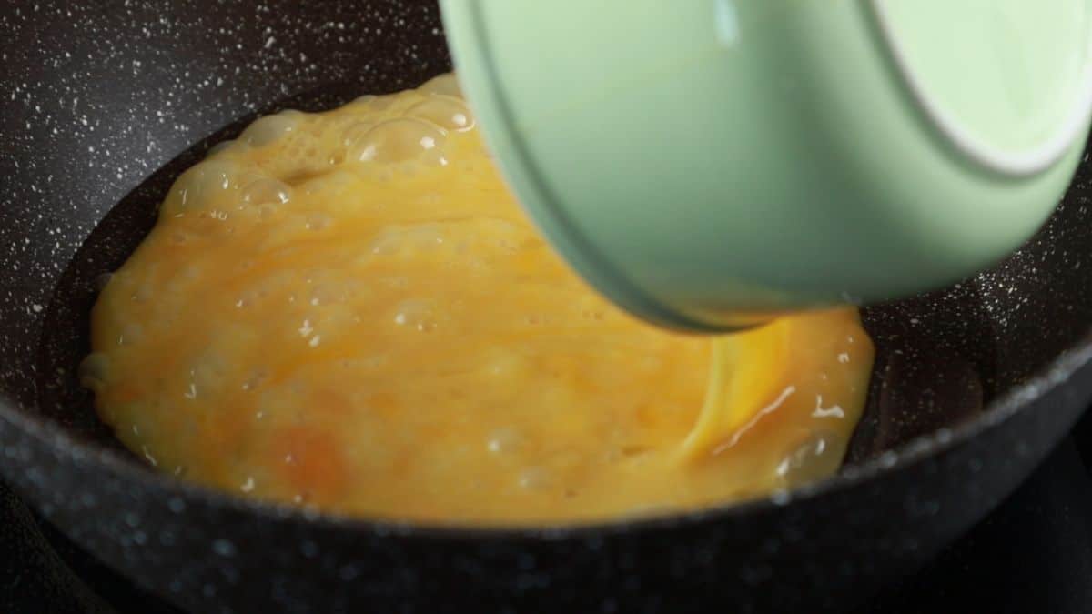 eggs being poured into hot skillet