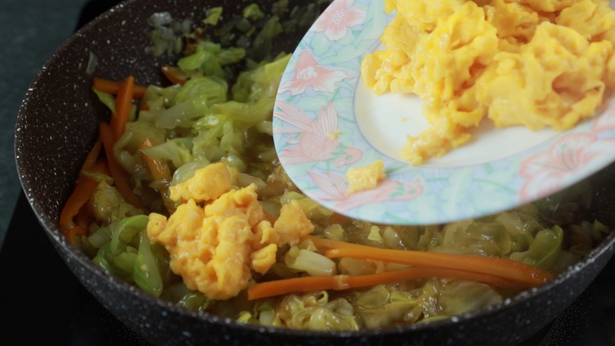 eggs being poured into skillet of stir fry