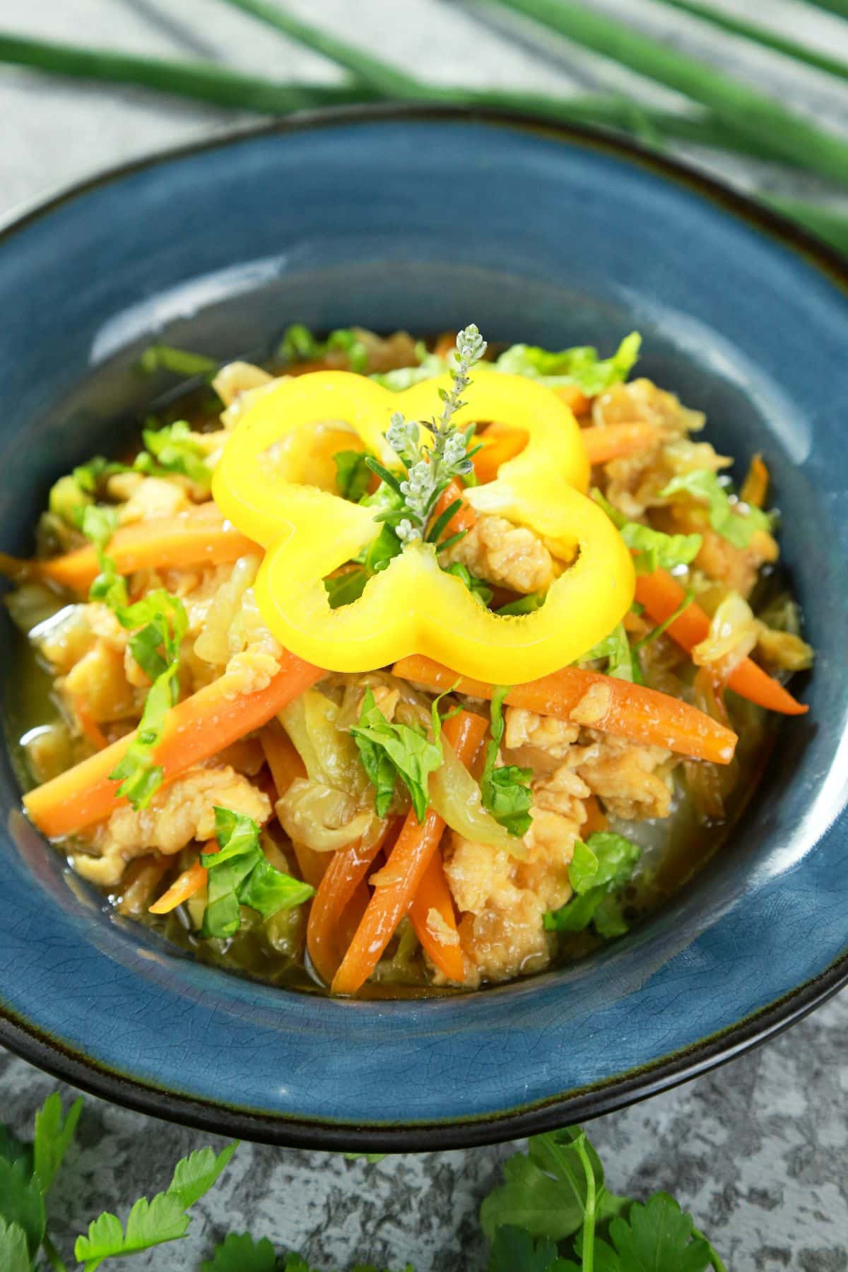 yellow bell pepper ring on top of cabbage with eggs stir fry in blue bowl
