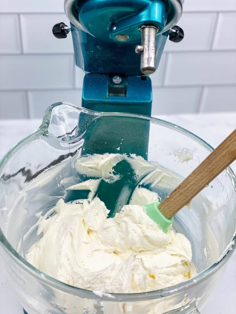 blue mixer with glass bowl of buttercream