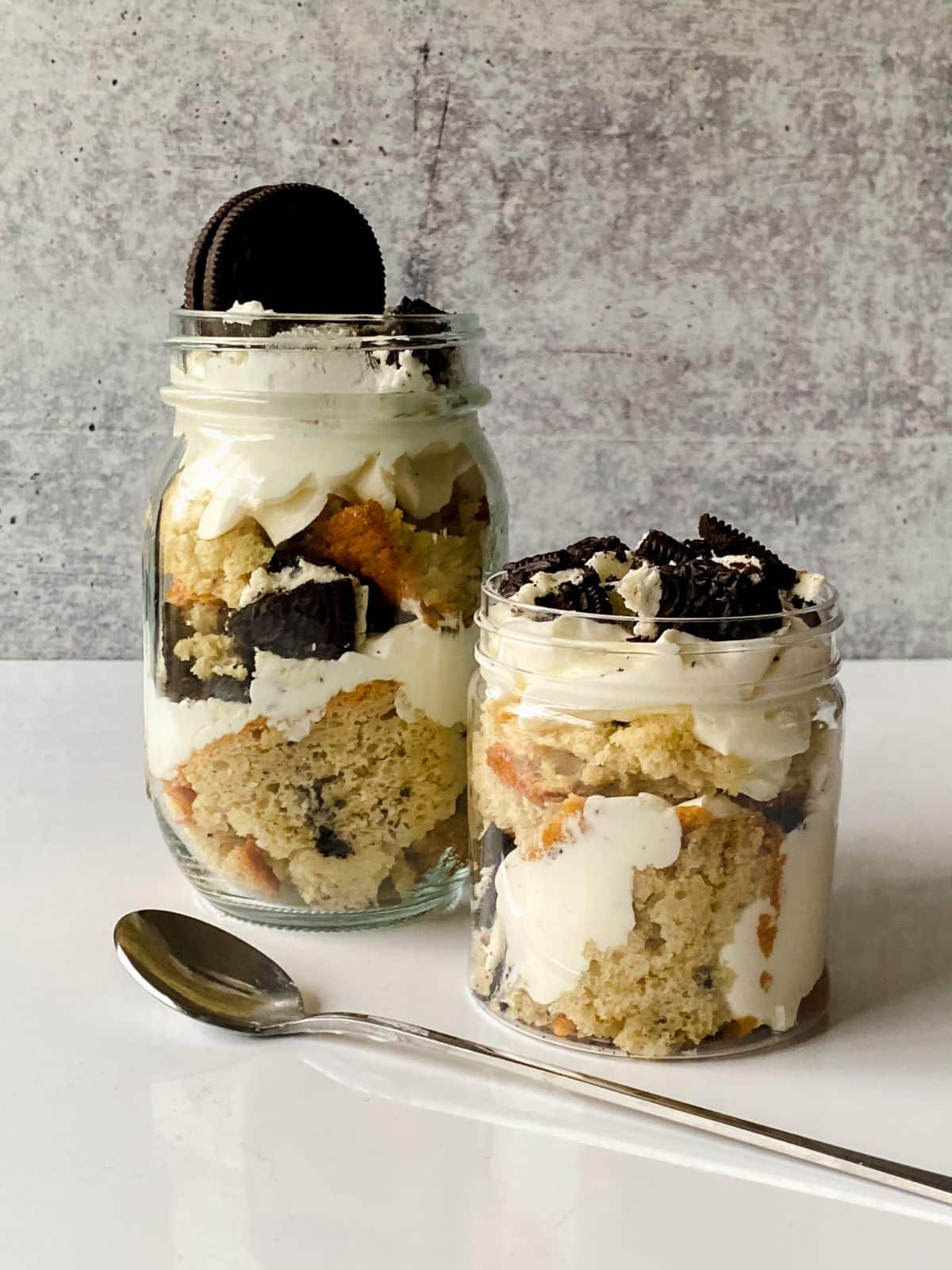cake in a jar with cake, cream, and cookies in jars on table