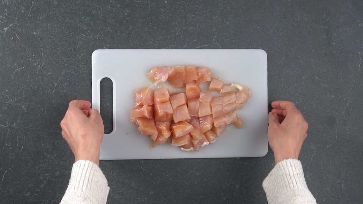 chicken breasts chopped into cubes on cutting board