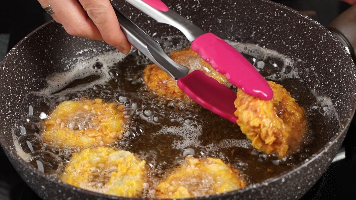 chicken rings in skillet being removed with pink tongs